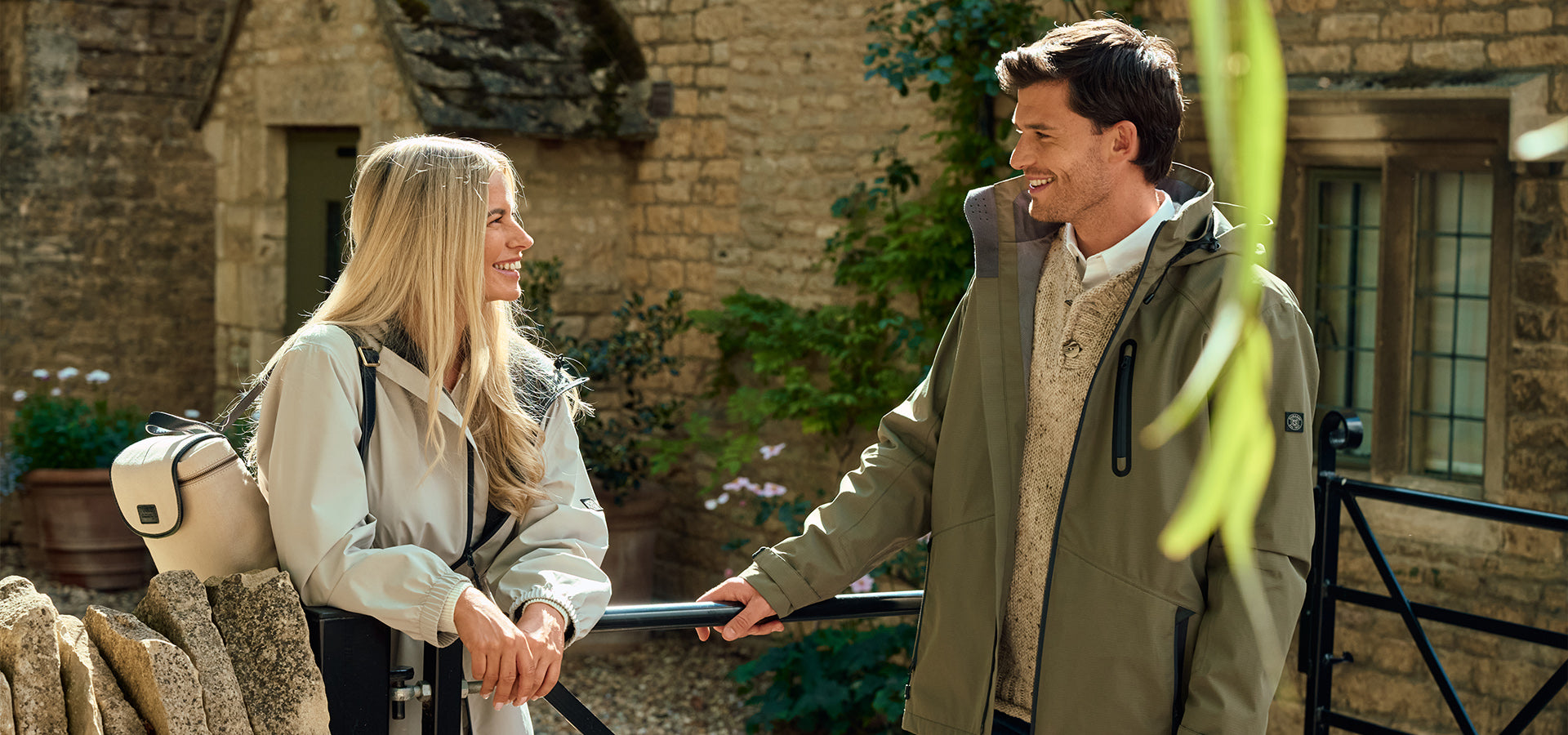 Two people standing outdoors in front of a stone building.