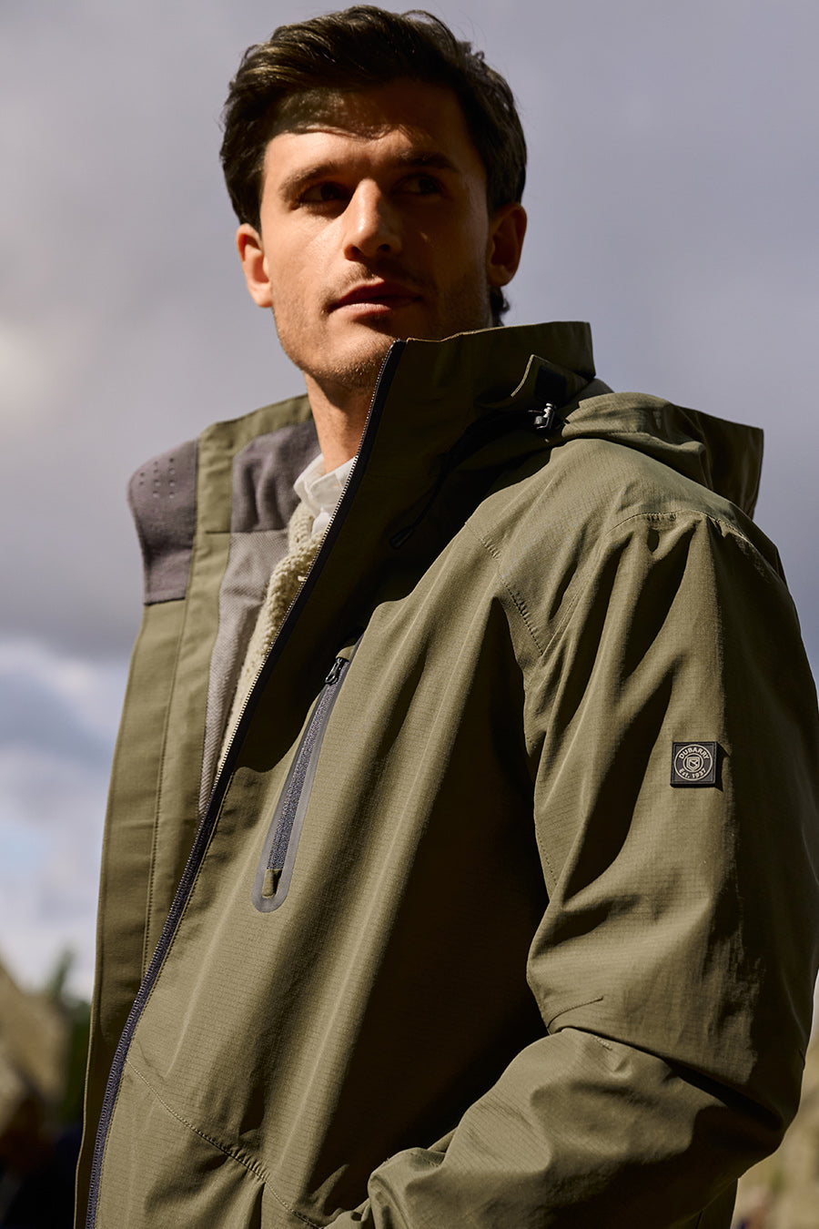 Man wearing a Dubarry green jacket with a logo on a cloudy day