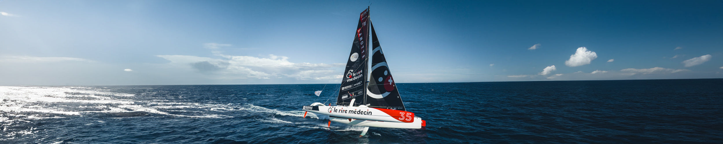 Wide image of Luke Berry's boat at sea on it's side gliding through the blue water on a sunny day