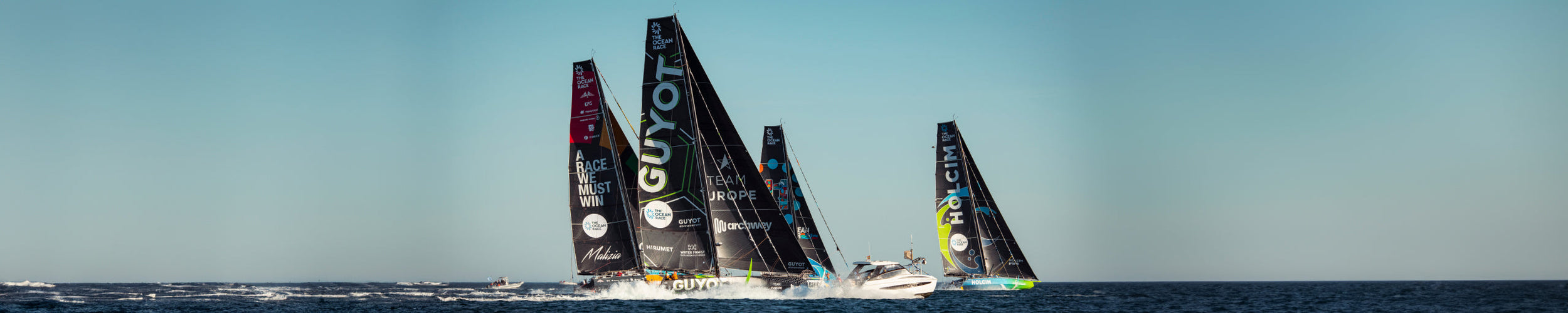 Wide image of Teams Guyot, Holcim, and other boats in the water during the Ocean Race 2023.