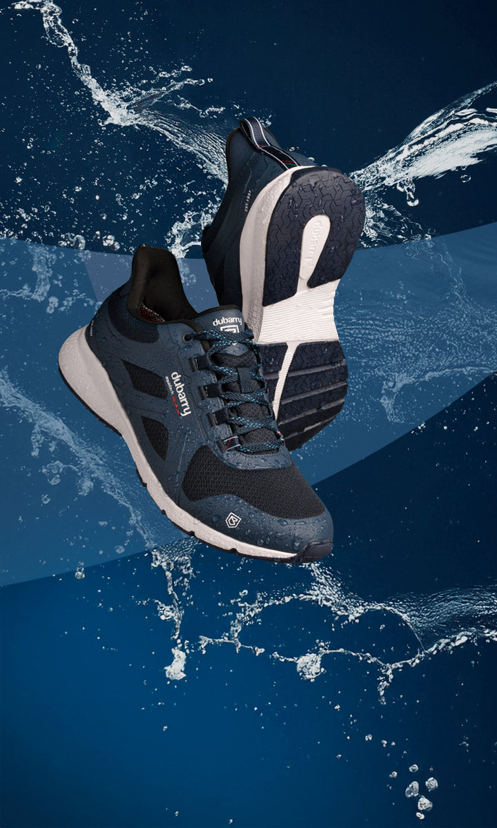 Blue and black athletic dubarry shoes with white sole on a blue water background